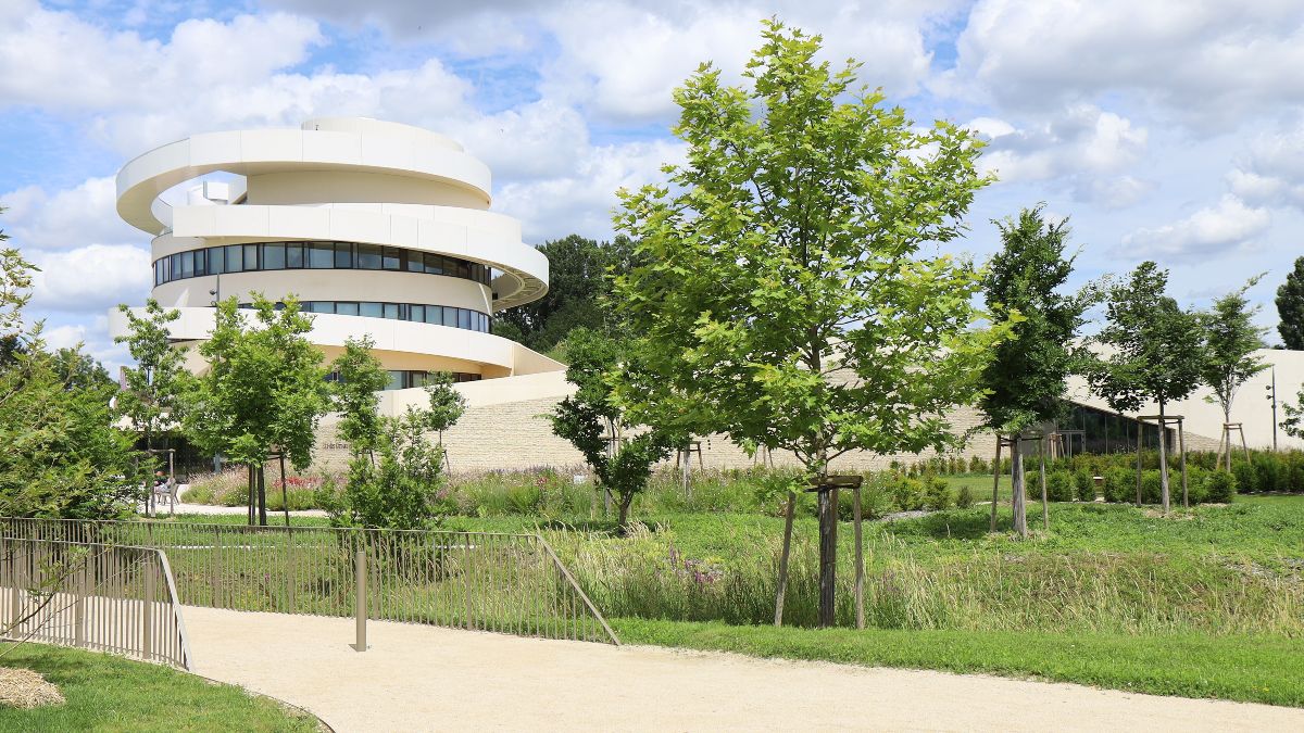 Fußweg, durch einen Park, der an einem Gebäude entlangführt